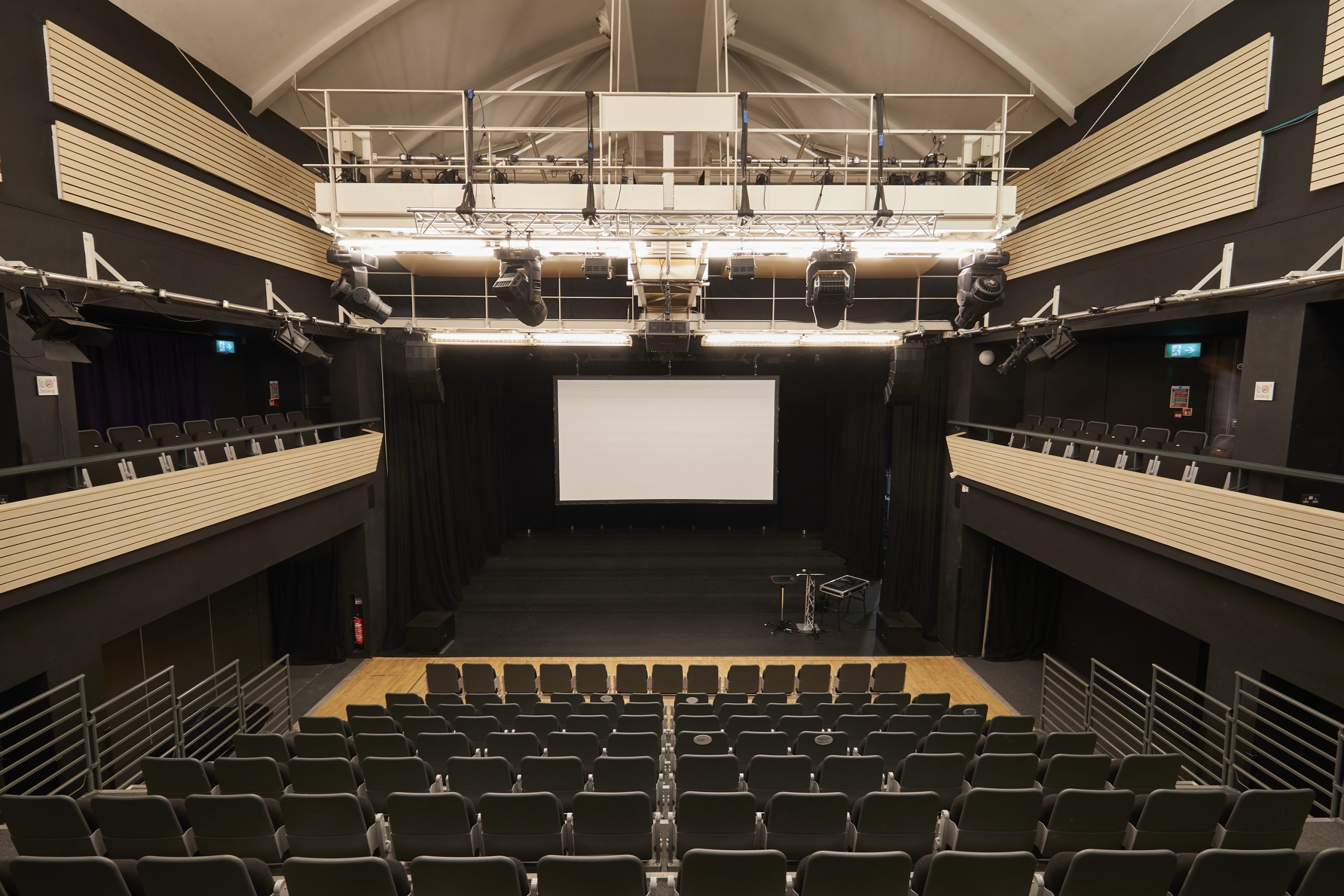A theatre with all lights up looking at a large screen