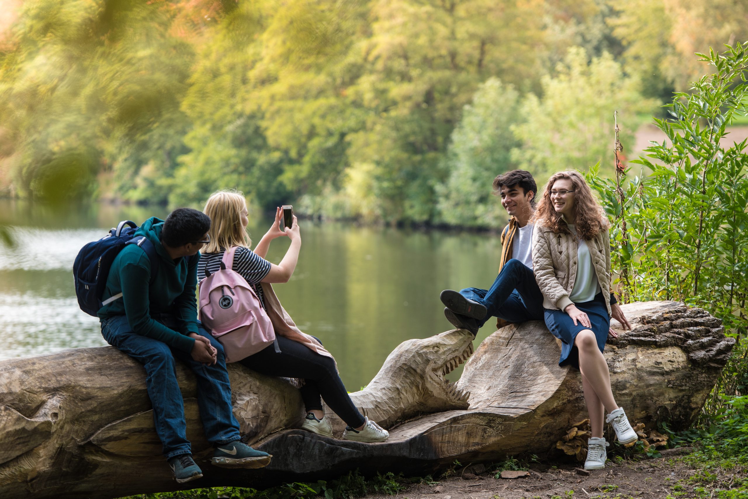 A group of people sat on a log next to a lake