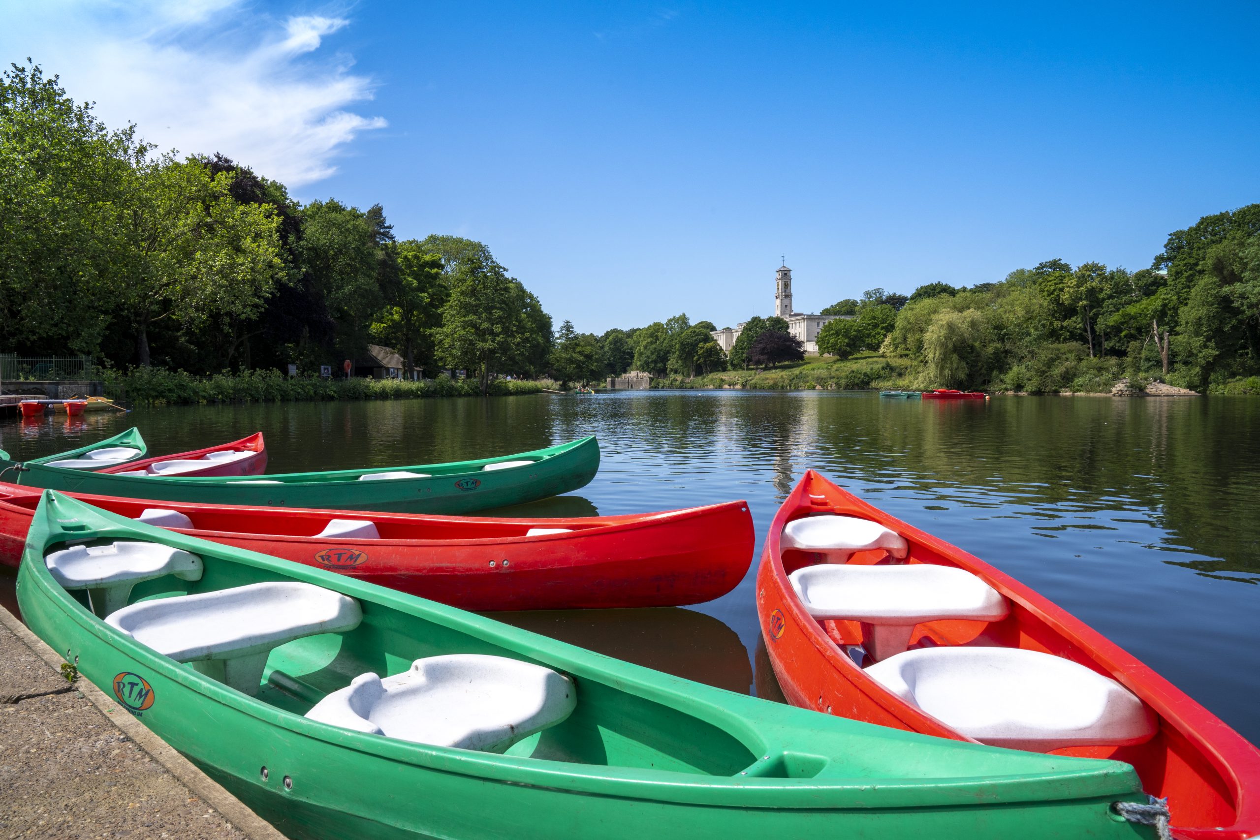 Colourful rowing boats sat at the side of the lake, with the Trent building in the background.