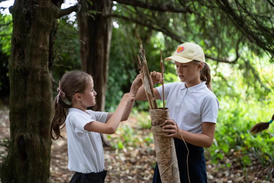 Two school girls holding a quiver containing wooden arrows in Highfields Park, Nottingham.