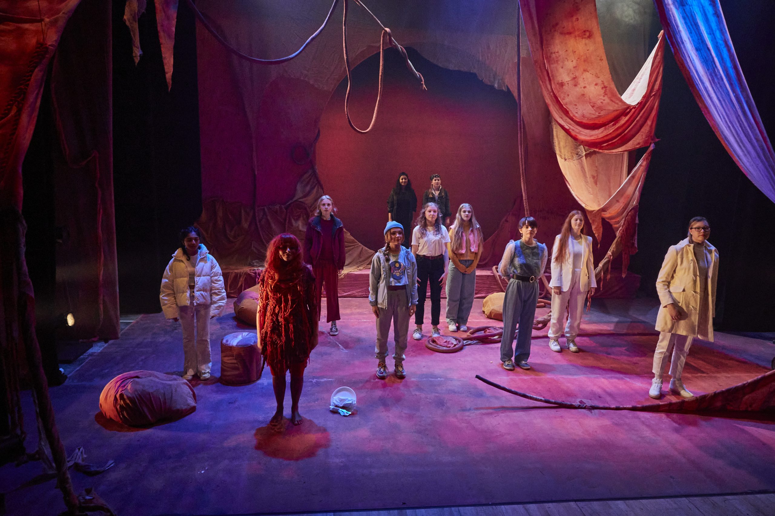 11 actors stand looking out at the audience before taking a bow