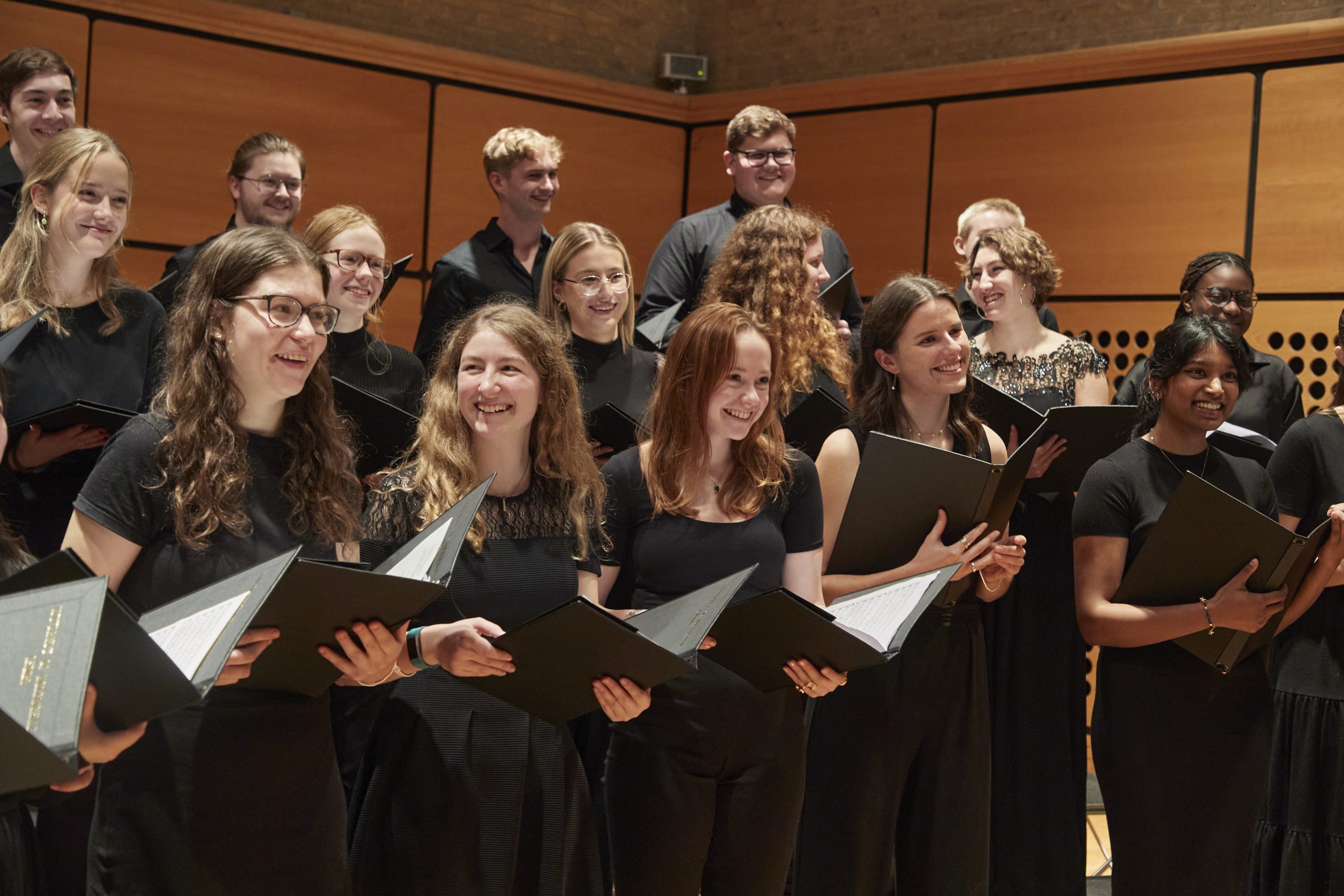 small choir all dressed in black stand and smile