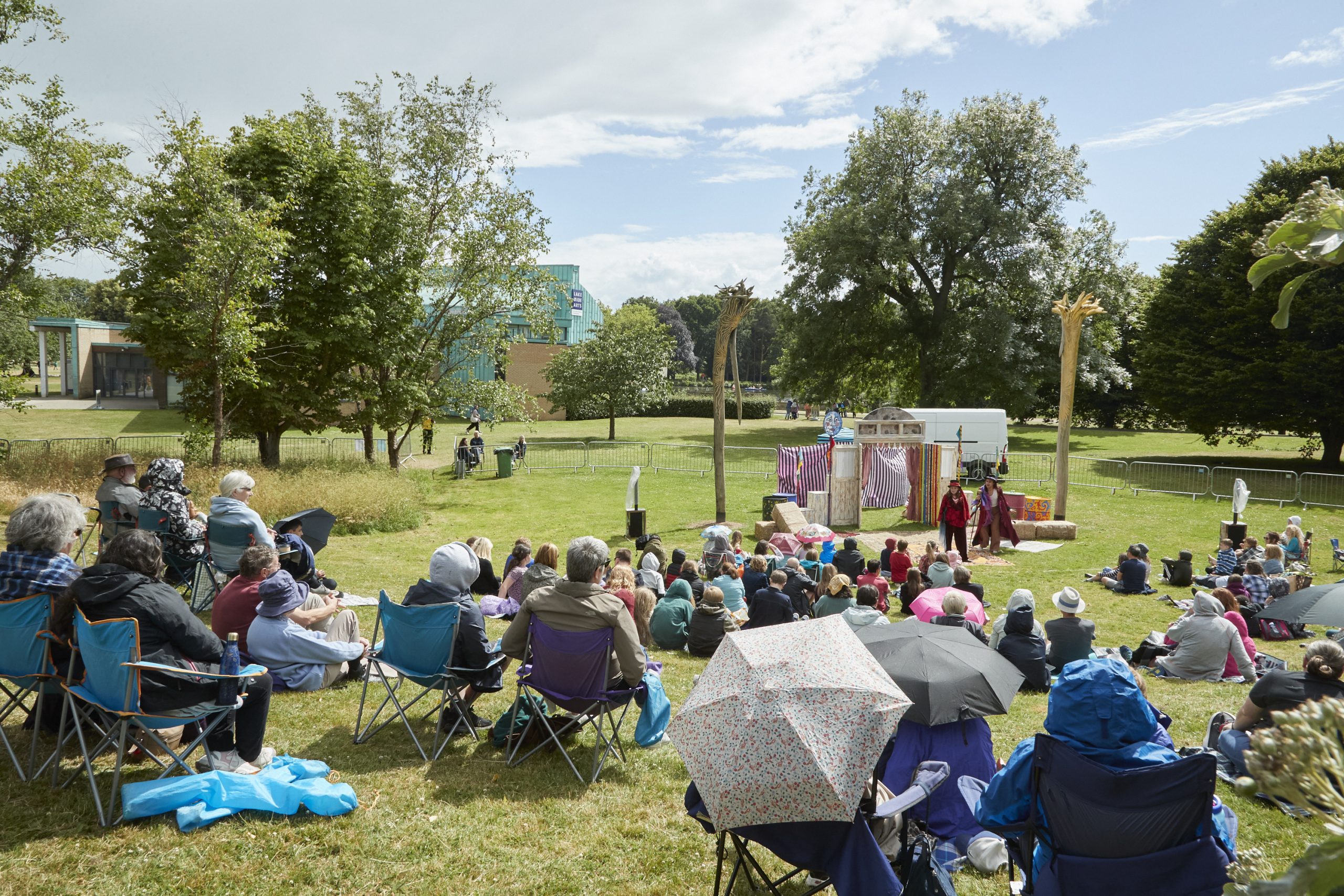 Families sat on grass watching theatre