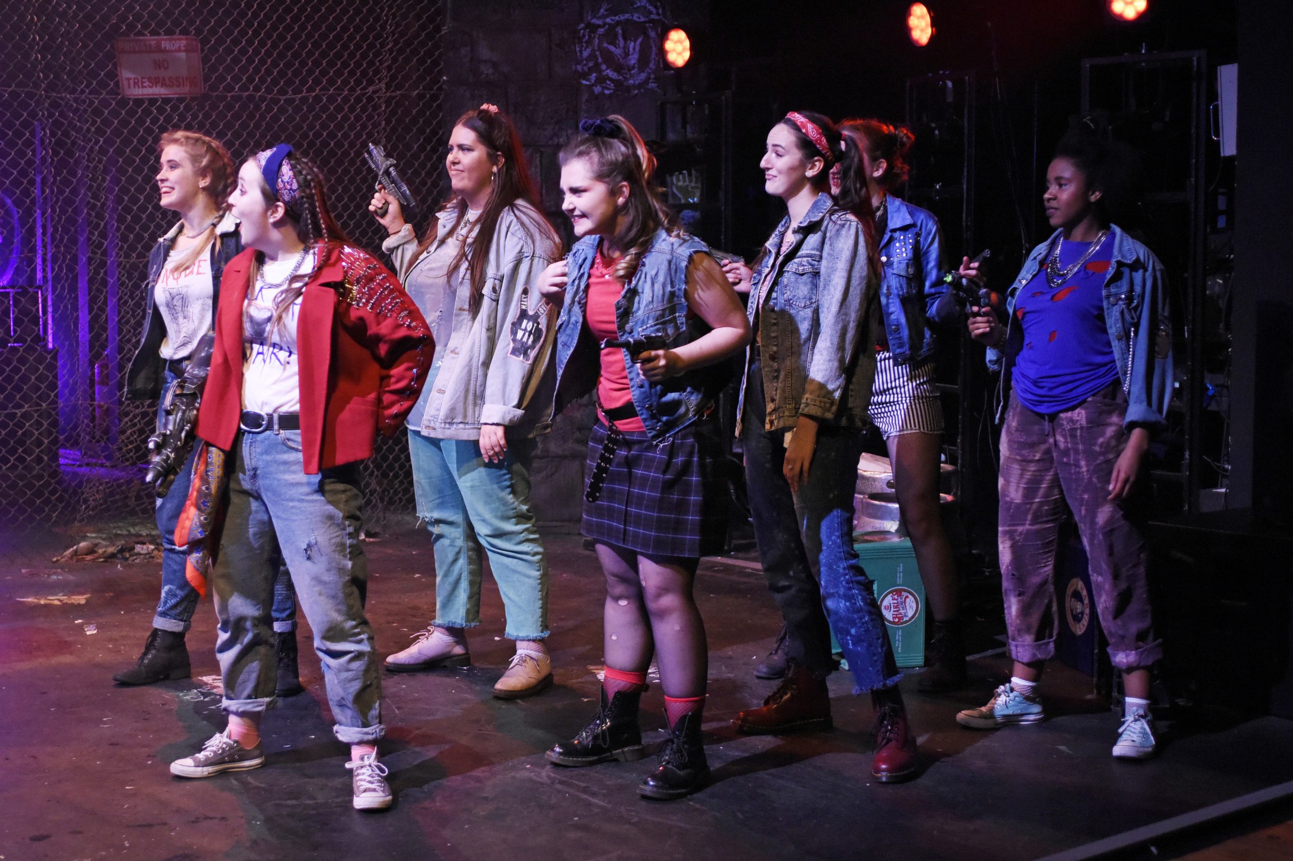 seven actors in edgy street clothes hold guns and look menacing