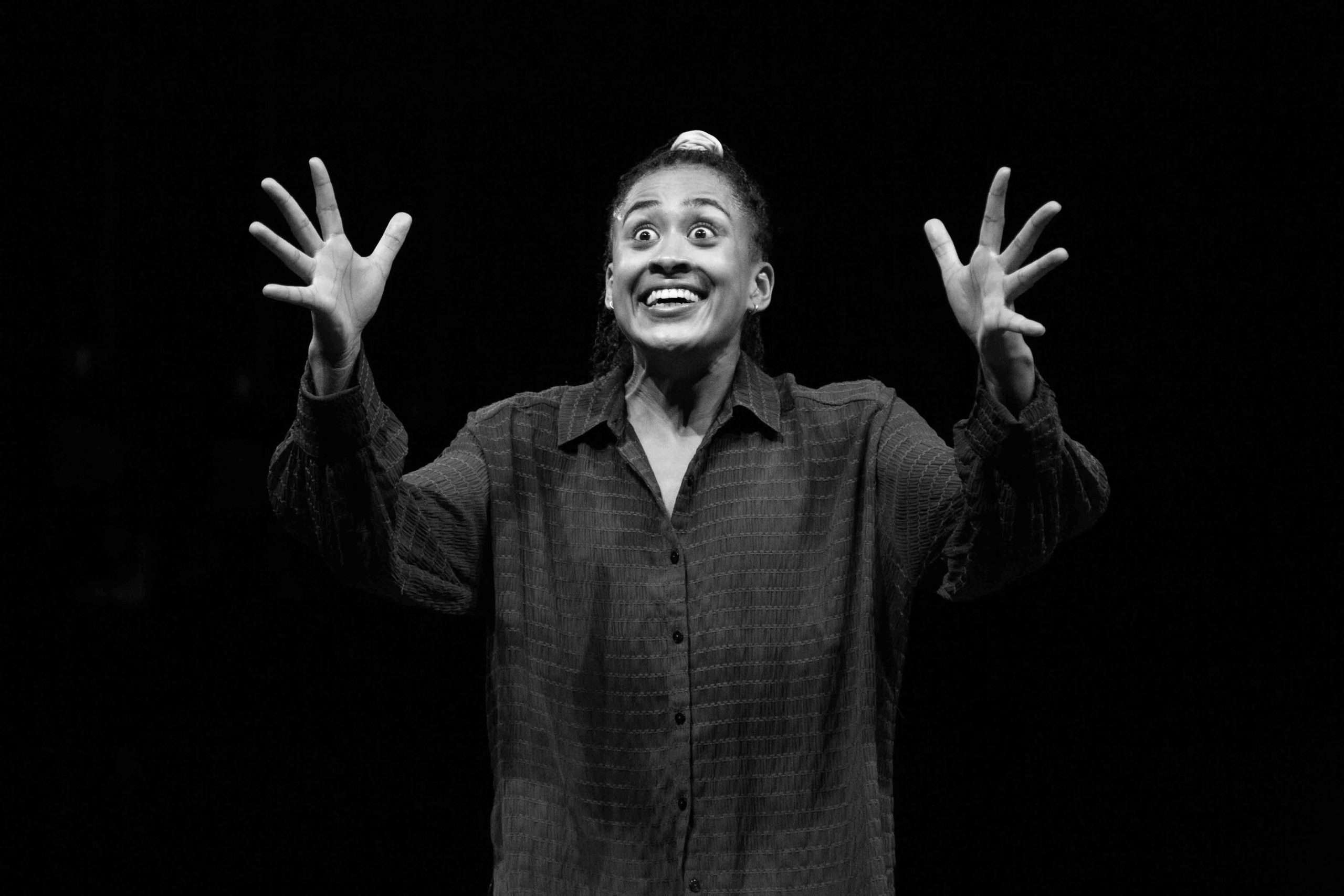 A black and white photo of a dances looking amazed with her hands out in front of her