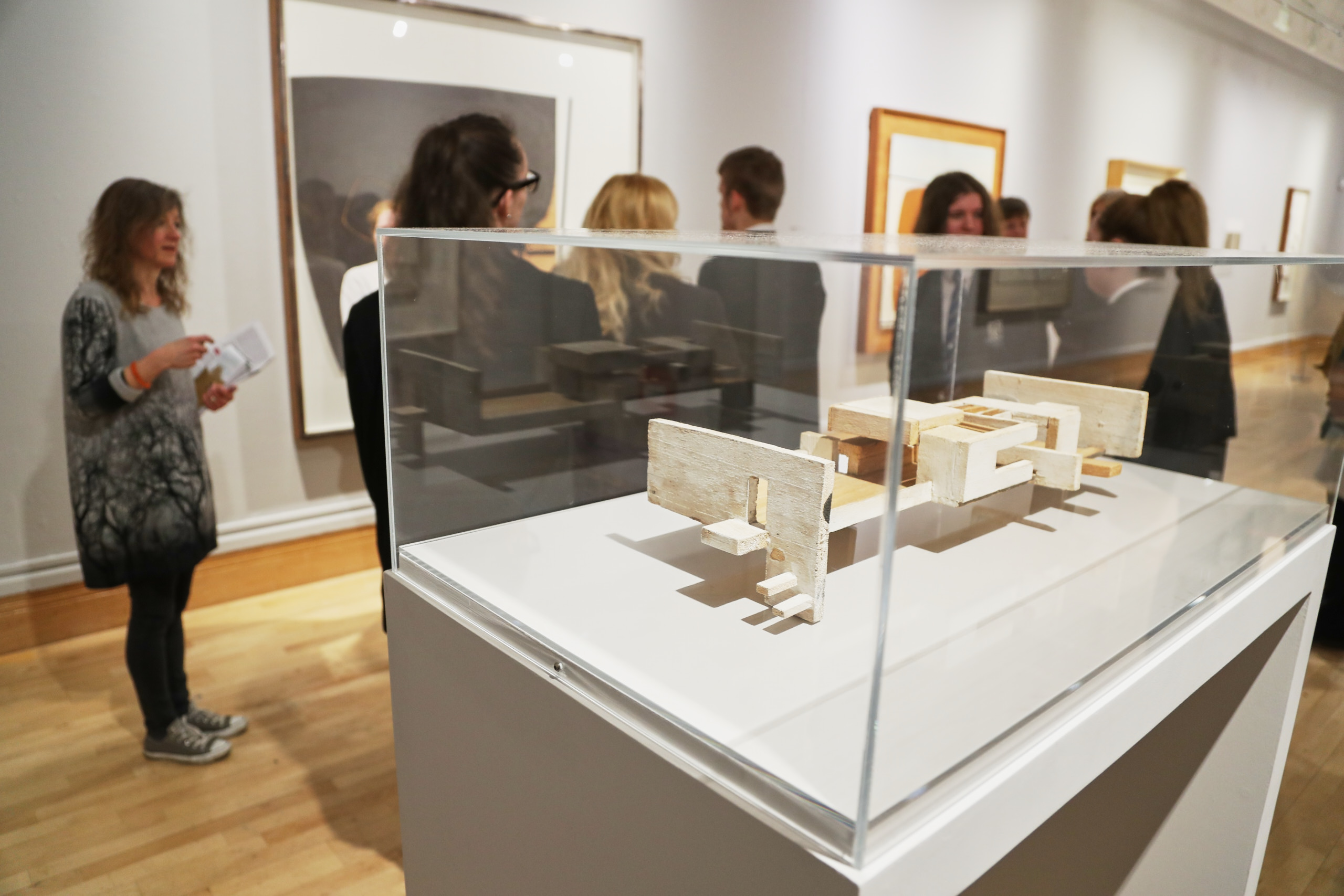A group of eight secondary school students in uniform looking at paintings in Lakeside Arts’ Djanogly Gallery, with a sculpture on a plinth in the foreground.