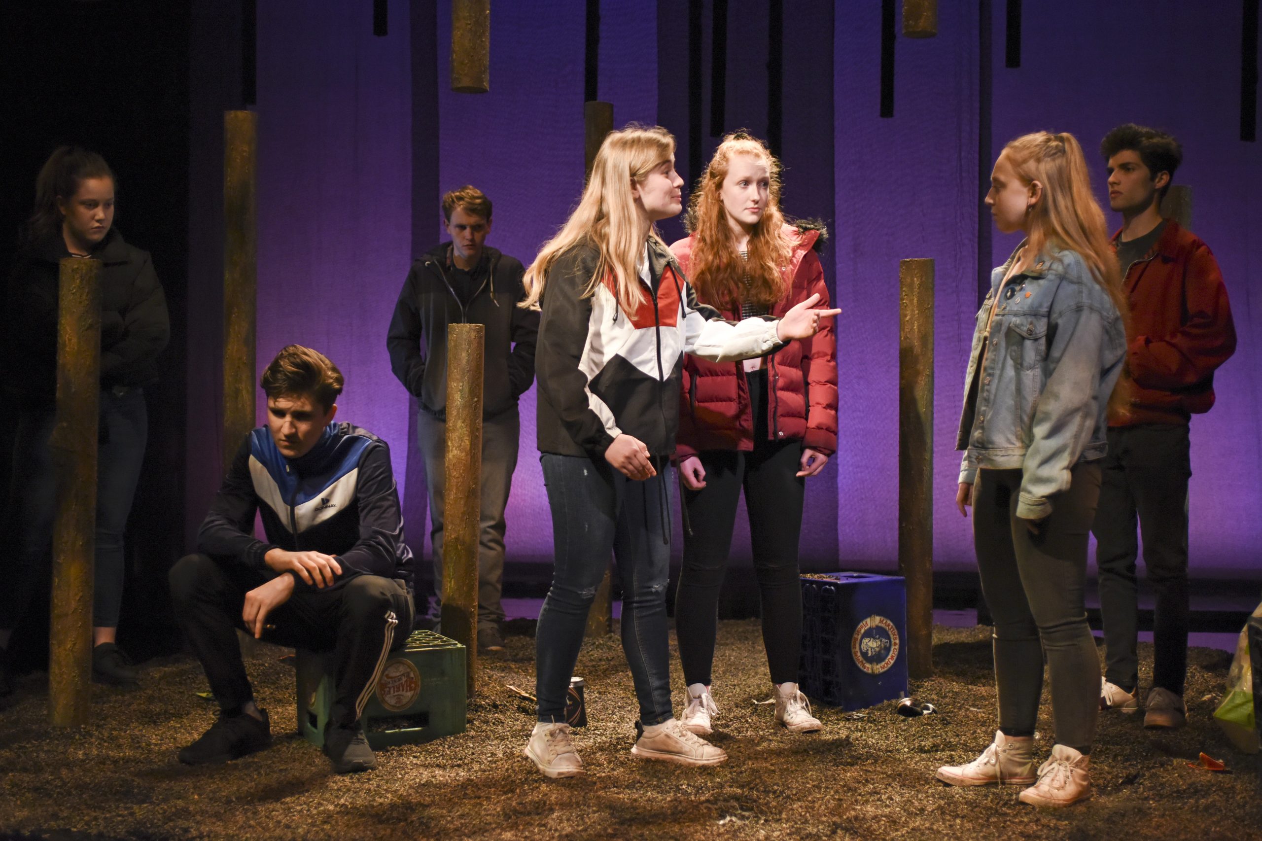 a group of actors confront each other whilst two people look sad next to them