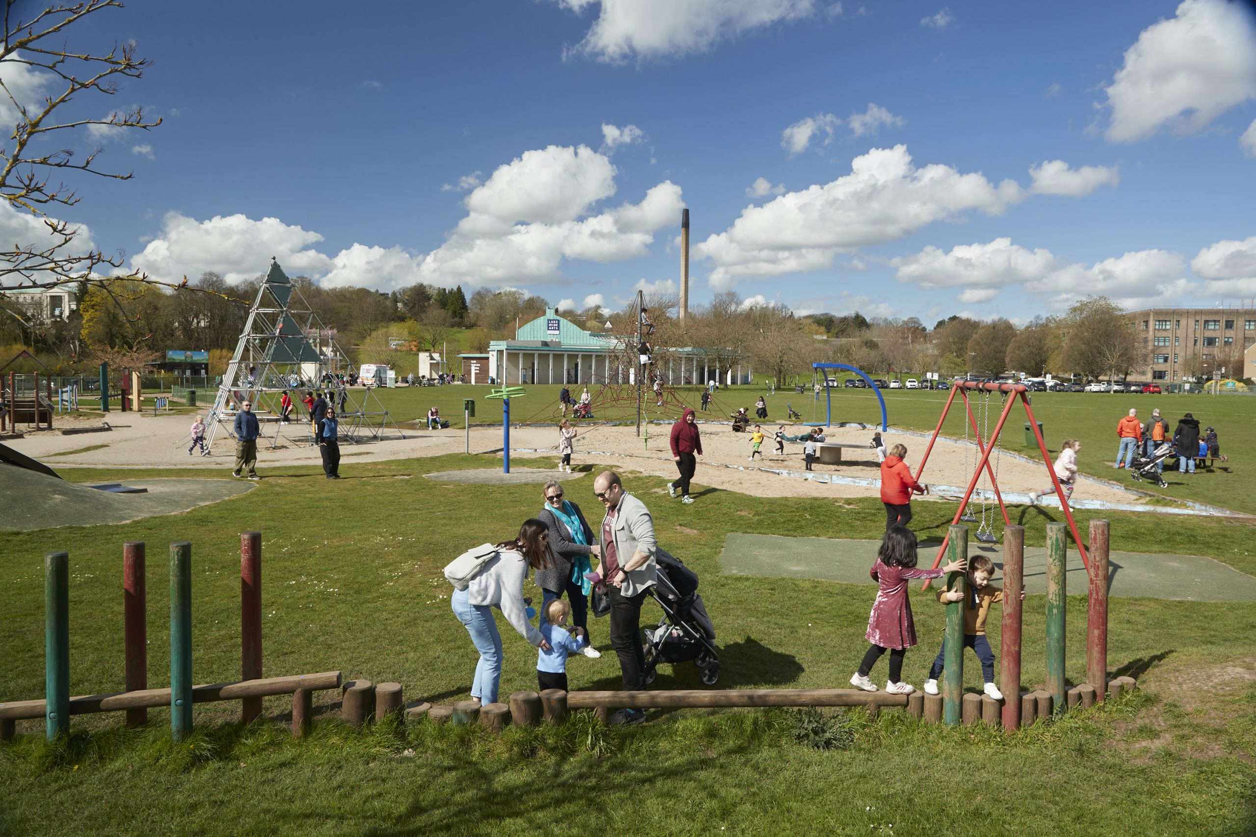 Families playing on a park, with blue sky in the background.