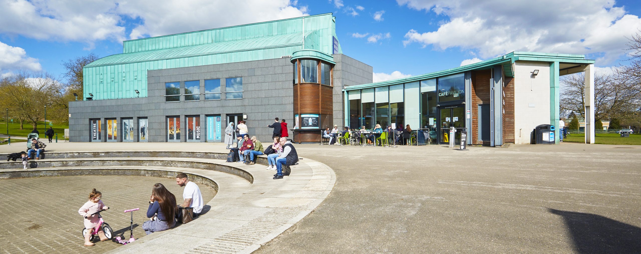 The exterior of the DH Lawrence pavilion a green-roofed building with large windows and a cafe